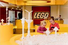 two children playing with legos in a playroom at a mall or office building