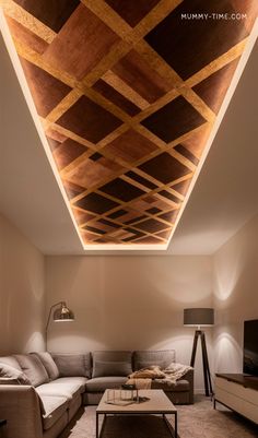 a living room with couches and a coffee table under a wooden ceiling that has geometric designs on it