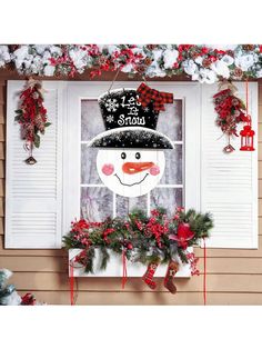 a snowman is hanging on the window sill in front of some christmas decorations