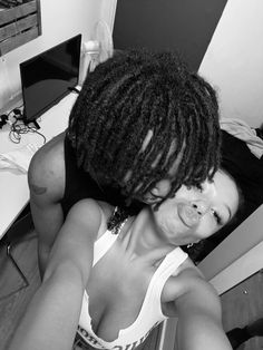 a black and white photo of a woman with dreadlocks sitting in front of a computer desk