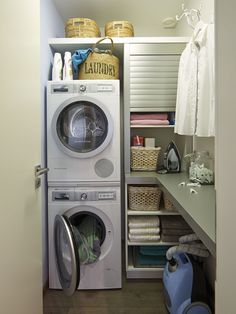 a washer and dryer in a small room next to a shelf with laundry items