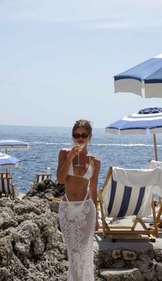 a woman in a white dress standing on the beach