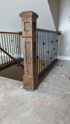 a wooden stair case in the middle of a room with white walls and flooring