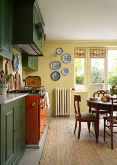 a kitchen with green cabinets and wooden table surrounded by plates hanging on the wall above it