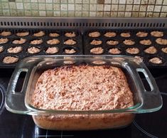 a baking dish on top of an oven with muffins in the back ground