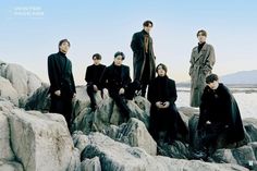 a group of people standing on top of rocks near water