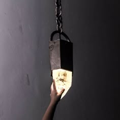 a hand holding a light that is attached to a chain with a block on it