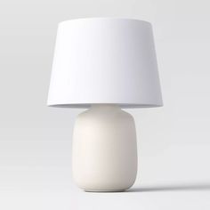 a white table lamp with a white shade on it