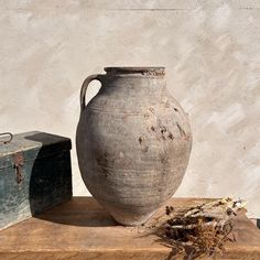 an old vase sitting on top of a wooden table next to a box and trunk