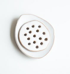 a small white plate with holes in the center on a white surface, it appears to be made out of porcelain