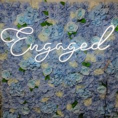 a blue and white flower wall with the word engaged spelled in cursive writing