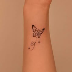 a small tattoo on the wrist of a woman with a butterfly and stars around it