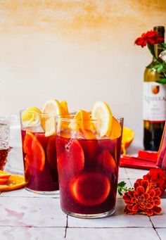 two glasses filled with red wine and orange slices