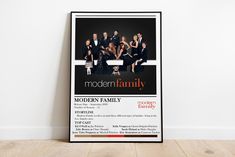 the modern family poster is hanging on the wall next to a wood floor and white walls