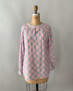 "An adorable spring blouse by Levi's from the late 1970s - early 1980s. Made from a pastel plaid cotton blend in shades of pale pink, blue and green, the blouse has a gathered neckline with a front button closure and keyhole, and long, puffy bishop sleeves that can also be rolled/cuffed and buttoned in place with the attached tab. Looks so cute tucked into high waisted jeans! Measurements Tag: Levi Strauss Material: 55% Cotton 45% Polyester Size: tagged a vintage size 10 and fits a modern small Relaxed Fit Plaid Blouse For Daywear, Plaid Long Sleeve Top For Spring, Spring Long Sleeve Plaid Top, Preppy Cotton Tops For Daywear, Preppy Pink Tops For Fall, Preppy Plaid Summer Tops, Summer Preppy Plaid Tops, Spring Plaid Relaxed Fit Tops, Plaid Relaxed Fit Tops For Spring