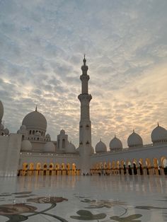 a large white building with many arches and domes on the top, in front of a cloudy sky