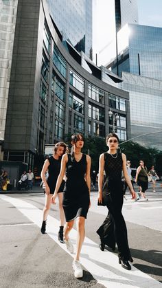 three women walking down the street in front of tall buildings