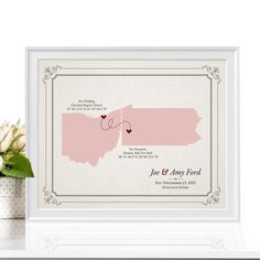 a white frame with a pink state map on it and a vase filled with flowers