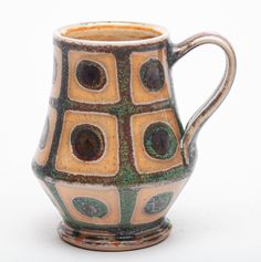 a brown and green vase sitting on top of a white table