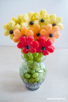 a glass vase filled with fruit and flowers