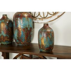 three vases sitting on top of a wooden table next to a wall mounted art piece