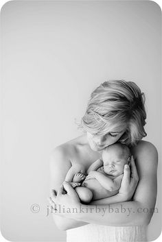 a black and white photo of a woman holding a baby in her arms while she is breastfeeding