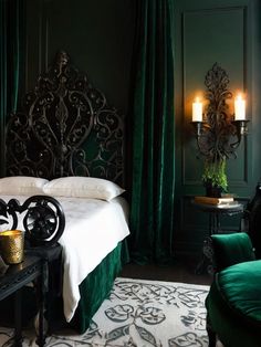 a bedroom with dark green walls and white bedding, black headboard and foot board