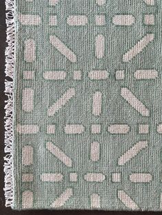 a green and white rug with fringes on the bottom, in front of a black background