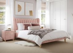 a bedroom with a pink bed and white walls, carpeted flooring and two windows