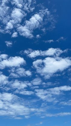 the airplane is flying high in the blue sky with fluffy white clouds above it,