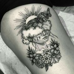 a woman's thigh with a sun and clouds tattoo on her leg, next to flowers