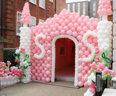 a pink and white balloon arch with baby shower sign on it's front door