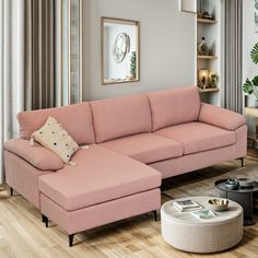 a living room with a pink sectional couch and coffee table in the corner, surrounded by curtains