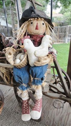 a scarecrow doll sitting on top of a wooden wagon with chickens in its lap