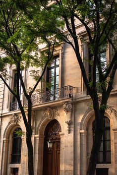 an old building with many windows and balconies on the front, surrounded by trees