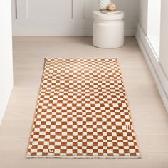 a white toilet sitting next to a brown and white checkered rug