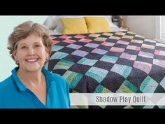 a woman standing in front of a bed with a quilt on it and the words shadow play quilt