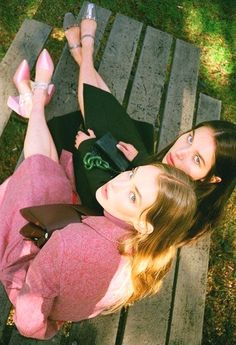 two women are sitting on a wooden bench