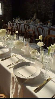 the table is set with white flowers and silverware