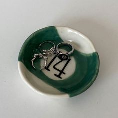 a small green and white bowl with a pair of scissors in the middle of it