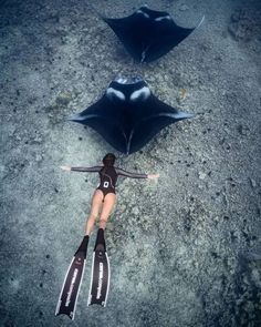 two people in wetsuits are laying on the ground next to an upside down umbrella