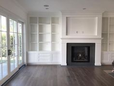 an empty living room with wood floors and white bookcases on either side of the fireplace