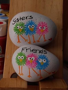 two painted rocks with the words sisters and friends on them sitting on a wooden stand