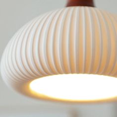 a close up of a light fixture on a white wall with a red object in the background