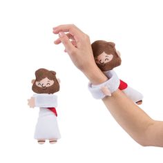 a hand holding a small doll with jesus on it's arm next to another toy