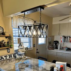 a kitchen with a marble counter top next to a white refrigerator freezer under a light fixture