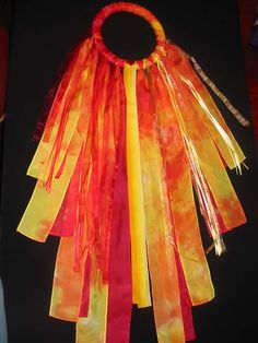 an orange, yellow and red scarf hanging from a black tablecloth covered table top