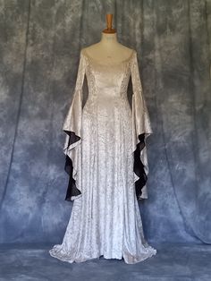 Medieval Gown,Elvish Dress,Celtic Gown,Custom Made,Hand Fasting Dress,Robe Medievale,Robe Elfique,Renaissance Dress,Elvira. Elvira, a medieval wedding dress, elegant styled in silver crushed velvet. Back corset style lacing allows for a little adjustment. The inner sleeves are in a soft organza. Elvira is also pictured with a cloak, made for a client for a Halloween wedding. It is designed and custom made by Gill Linley of frockfollies. Perfect as a Hand Fasting Dress or an Elvish Wedding Dress. CHECK OUT http://www.frockfollies.com for other designs and colour choices. FREE INSURED AND TRACKABLE SHIPPING Hand made in England by an experienced theatrical costumier, this medieval gown Elvira is available to order in a wide choice of colors and will be custom made to your measurements.  froc Elven Style Wedding Dress With Historical Design, Elven Wedding Dress With Historical Design, Elegant Dresses With Historical Design For Larp, Elegant Historical Design Dress For Larp, Elven Style Fitted Floor-length Dress, Elvish Medieval Dress For Weddings And Festivals, Elvish Medieval Wedding Dress For Medieval Festivals, Medieval Style Floor-length Dress For Fancy Dress, Floor-length Elven Medieval Dress For Larp