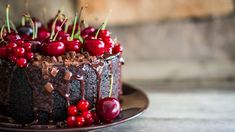 a chocolate cake topped with cherries and chocolate frosting