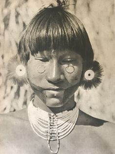 an old black and white photo of a native american woman with large earrings on her head